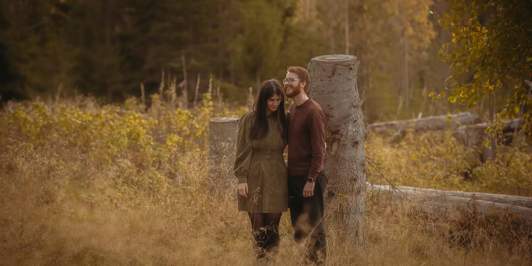 Amanda and Thomas standing together in an autumn forest.